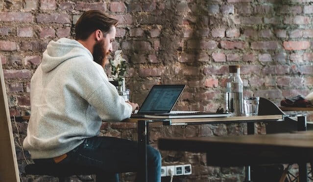 Man in beige hoodie working on a laptop